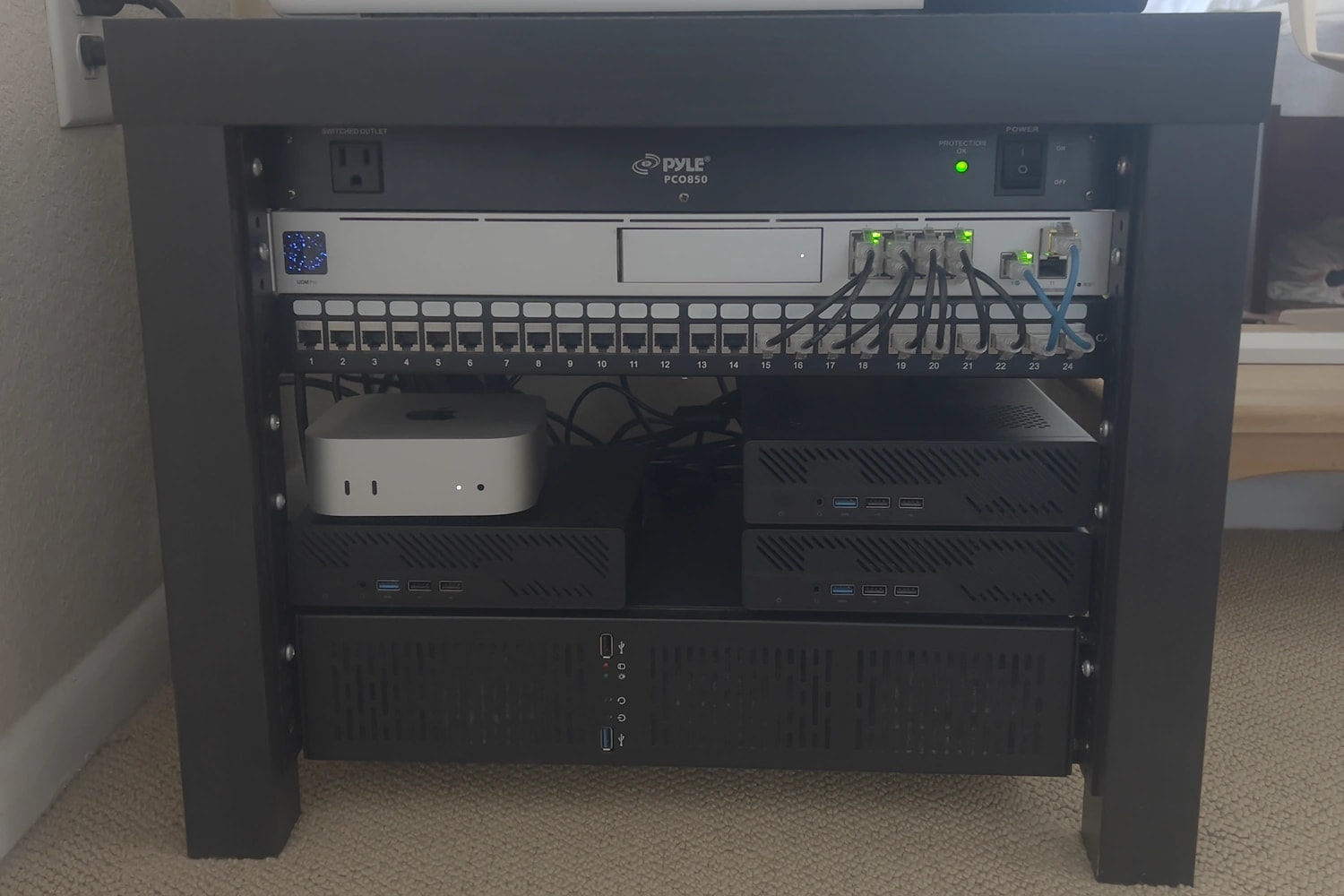 The rack: a PDU, the UDM Pro and a 24-port patch panel on top, the Mac mini and three Minisforum MS-01s in the middle, and the custom NAS across the bottom.